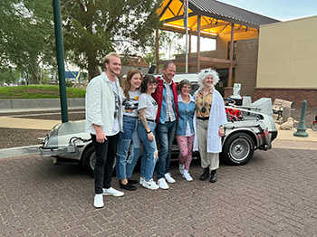 Family poses with Delorean Time Machine for surprise birthday party